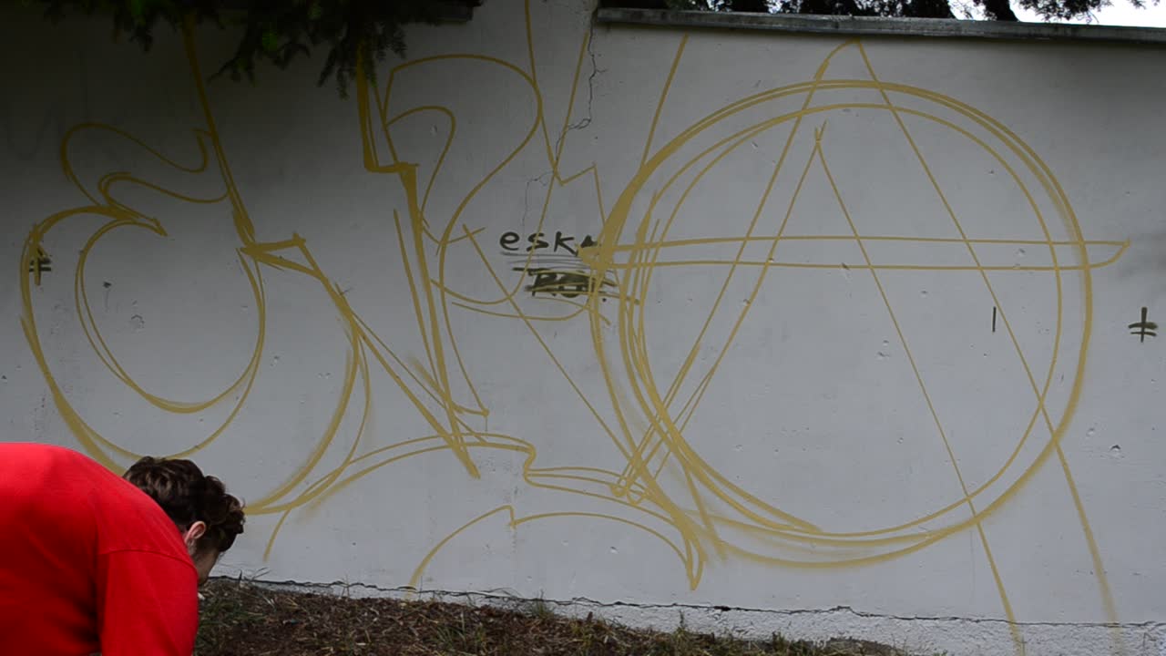 The artist draws graffiti on a fence, abstraction