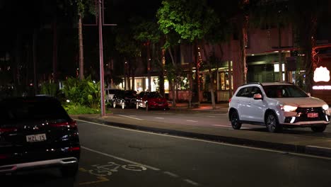 cars driving through a well-lit urban street