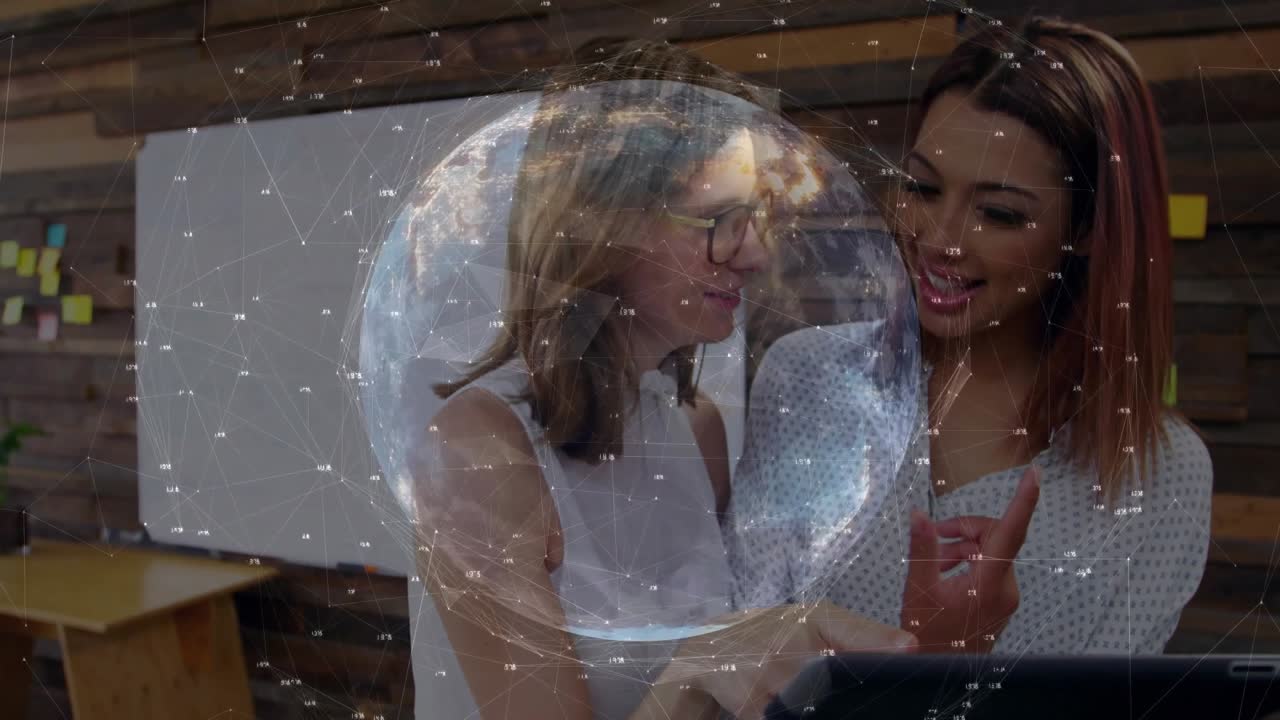 Globe overlay fading to reveal two colleagues tapping and pointing tablet in technology