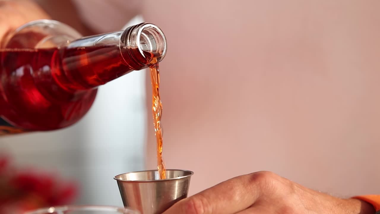 Bartender pouring a cocktail into a shot glass