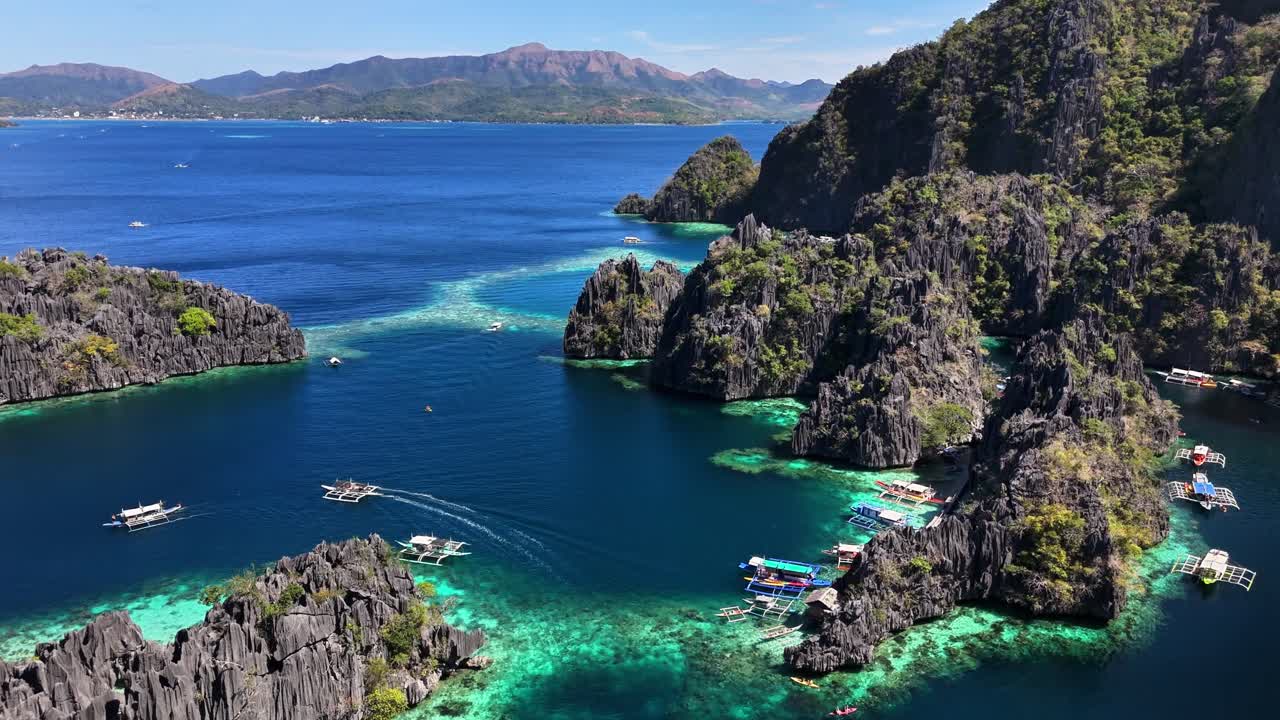 A stunning aerial view of Twin Lagoon in Coron, Philippines featuring turquoise waters, dramatic limestone cliffs, and traditional outrigger boats navigating the narrow channels