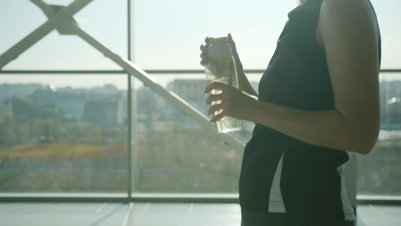 Woman Drinking Water in Modern Gym or Office