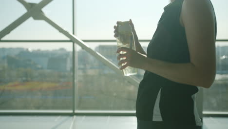 woman drinking water in modern gym or office