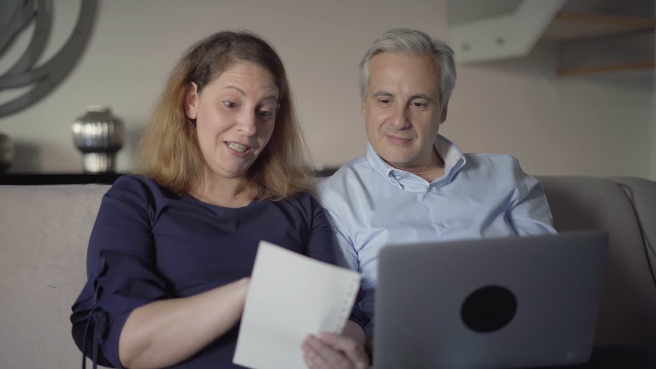 Casal de meia-idade comprando online com lista de compras