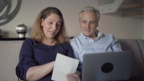 middle aged couple purchasing online with shopping list