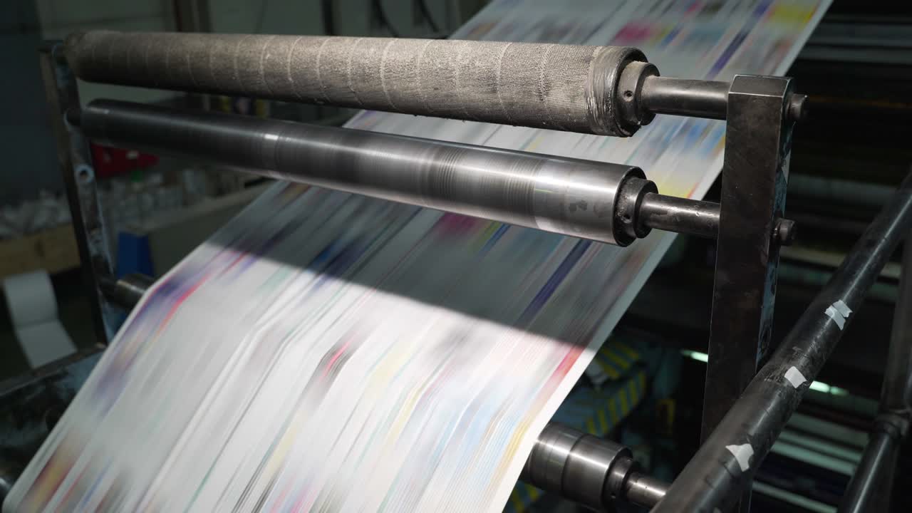 Color printing of newspapers on large machines, conveyor. Rolls of paper are drawn across the printing press. Printing house. Media, article, headline, daily news, print edition, journalism, politics
