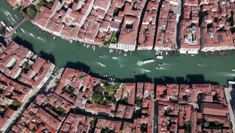 aerial drone timelapse of busy and beautiful venice canal with lots of boat traffic and pedestrians walking along canals and alleys