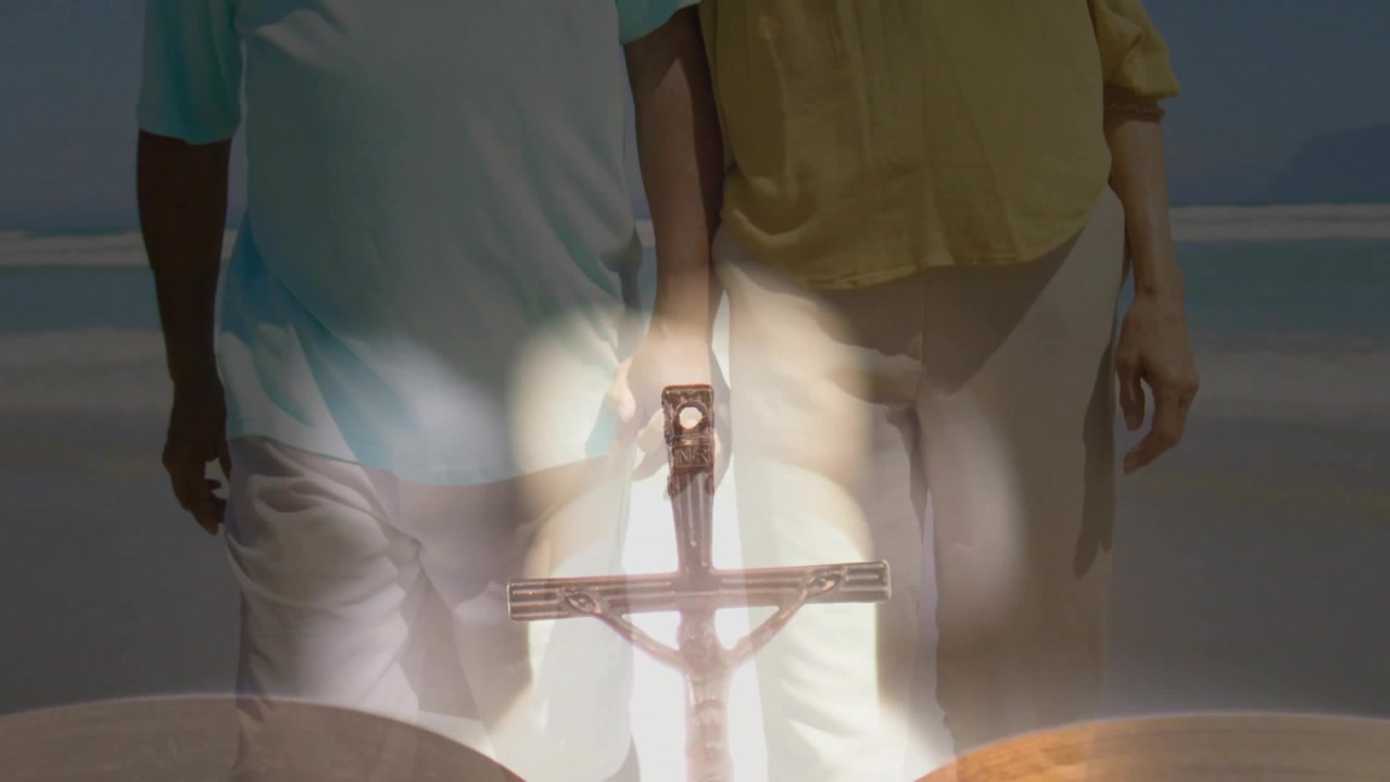 Senior man and woman walking along shore, bokeh initiating crucifix merging with bible for faith