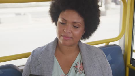 Happy-plus-size-biracial-woman-using-smartphone-in-bus