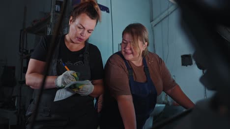 two women auto mechanics inspecting a car