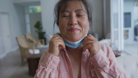 portrait of asian female patient wearing face mask, lowering mask and smiling to camera