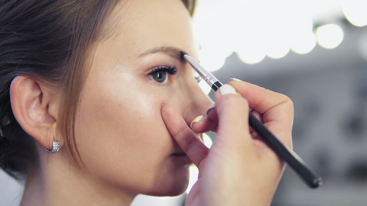 Makeup artist paints the eyebrows, doing eyebrow correction. Slow Motion shot