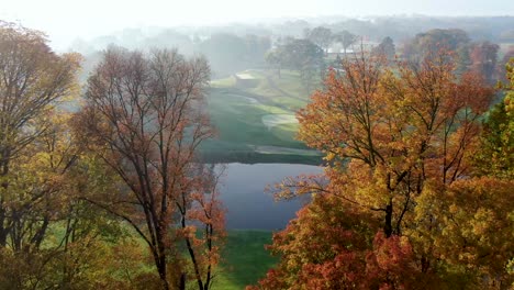 cinematic aerial reveal of lancaster country club, conestoga river, golf course greens, foggy autumn sunrise