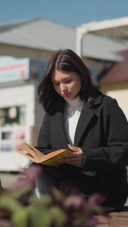 investigador sentado al aire libre en un día soleado con las piernas cruzadas, hojeando las páginas de un libro mientras está profundamente concentrado, las flores se balancean en la brisa cercana, y una máquina de fondo silba suavemente