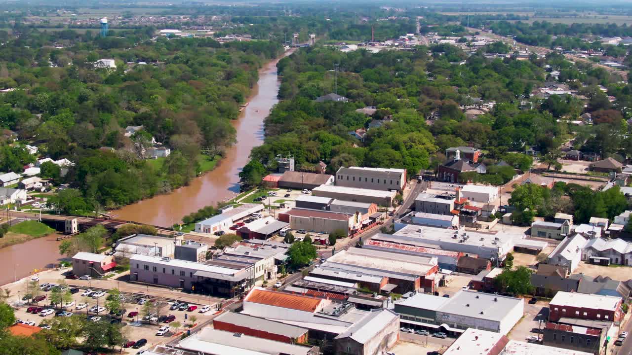 Drone shot of Main Street and Bayou Teche in New Iberia, Louisiana. The scene features downtown shops, a bridge over the bayou, and a marina, making it ideal for travel, tourism, and commercial use