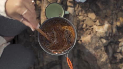 Toma-En-Cámara-Lenta-De-Una-Mujer-Haciendo-Chocolate-Caliente-Mientras-Acampa-Y-Disfruta-De-La-Naturaleza