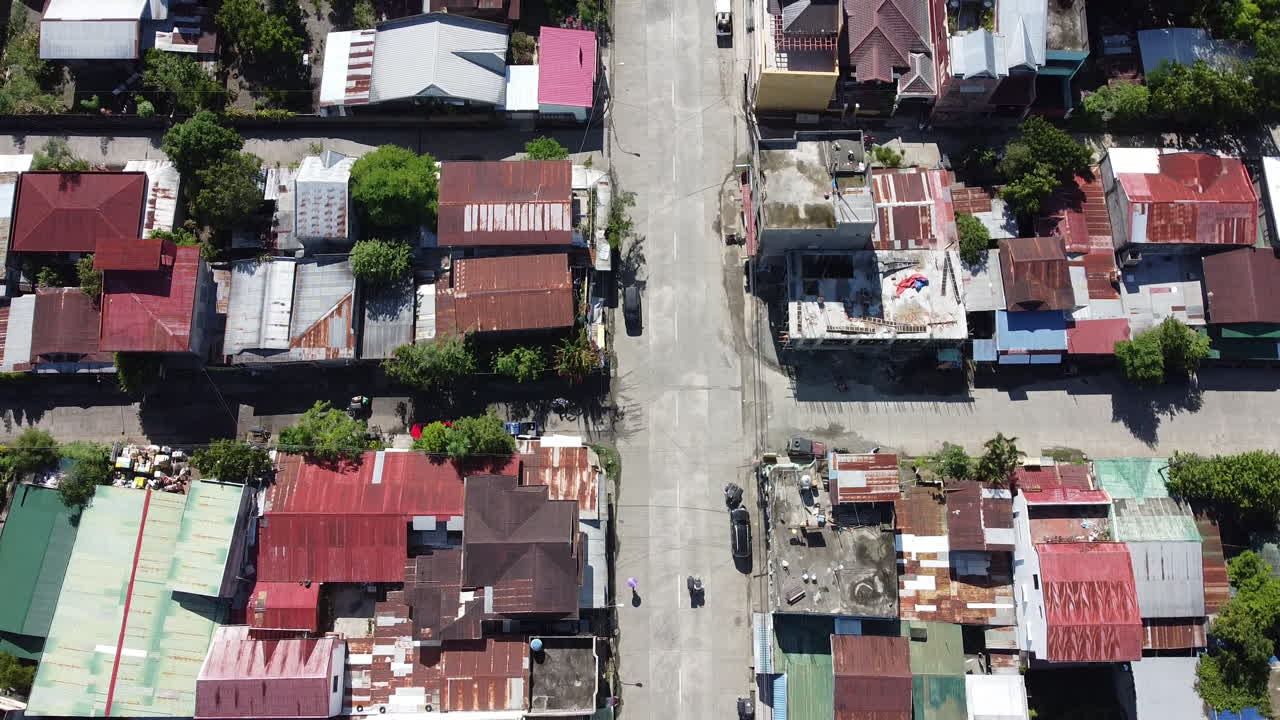 교통과 양철 지붕 주택이 있는 도시를 가로지르는 도로를 따라가는 드론