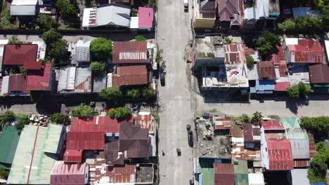 drone following road through city with traffic and tin roof homes