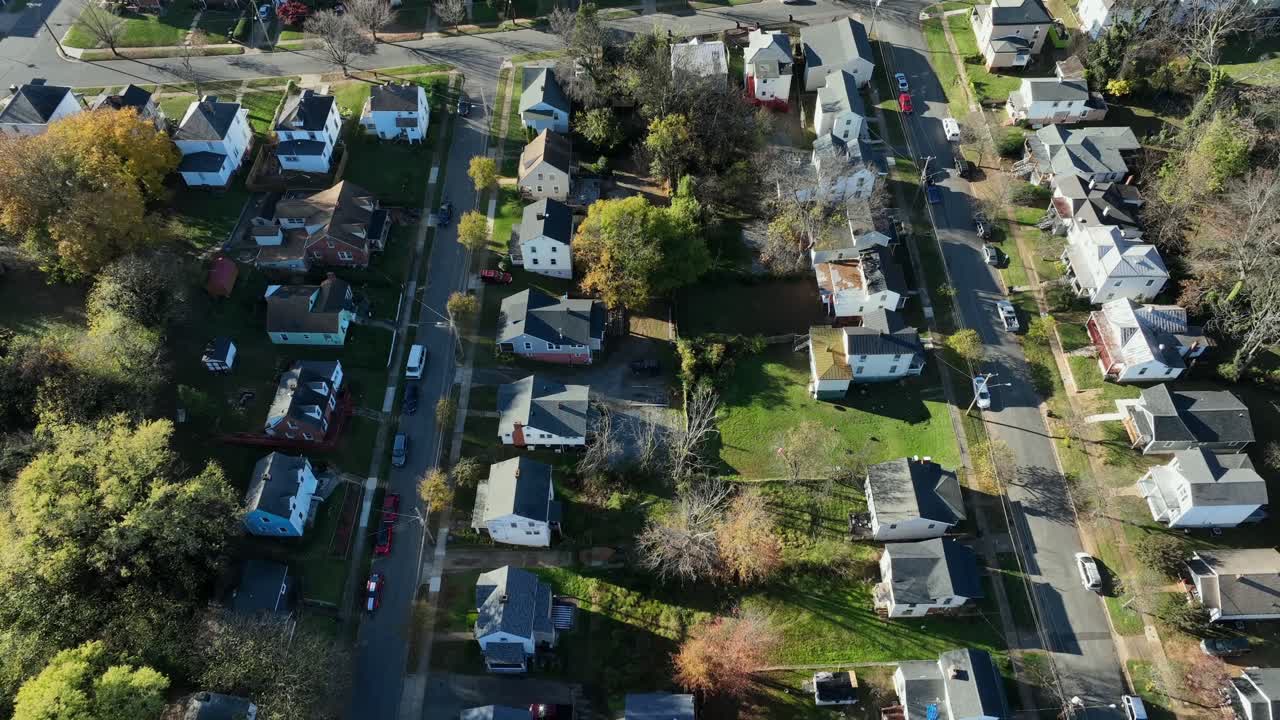 Straight street along American neighborhood in fall. Single family homes with colorful tree line road at sunset. Aerial top down shot. Virginia, USA.