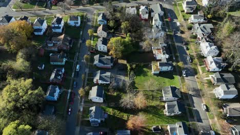 straight street along american neighborhood in fall. single family homes with colorful tree line road at sunset. aerial top down shot. virginia, usa.
