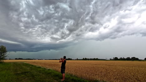 clouds moving in time lapse bringing dramatic storm, windy above a field, man is taking pictures, copy space