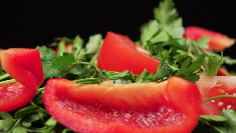 macro close up of colorful fresh parsley and tomatoes rotating on a black background