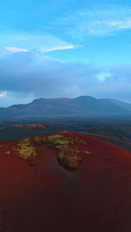 dark red ground in the landscape of iceland. mountain range at backdrop. aerial perspective. vertical video.