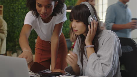 Joven-Mujer-De-Negocios-Asiática-Líder-De-Equipo-De-Trabajo-Compartiendo-Ideas-Creativas-Usando-La-Pantalla-De-Una-Computadora-Portátil-Que-Muestra-La-Investigación-Del-Proyecto-De-Un-Colega-En-Un-Lugar-De-Trabajo-De-Oficina-Ocupado