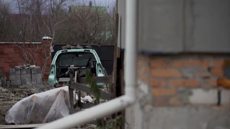 A-rusty-abandoned-car-in-the-parking-lot,-surrounded-by-a-fence-and-barbed-wire.-A-couple-of-cars-are-standing-in-a-sump-for-automotive-disassembly-or-metal-processing.-Restoration-of-a-retro-car.