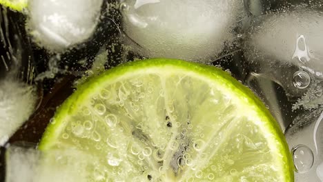 cóctel o bebida alcohólica, con lima y cubitos de hielo en el vaso