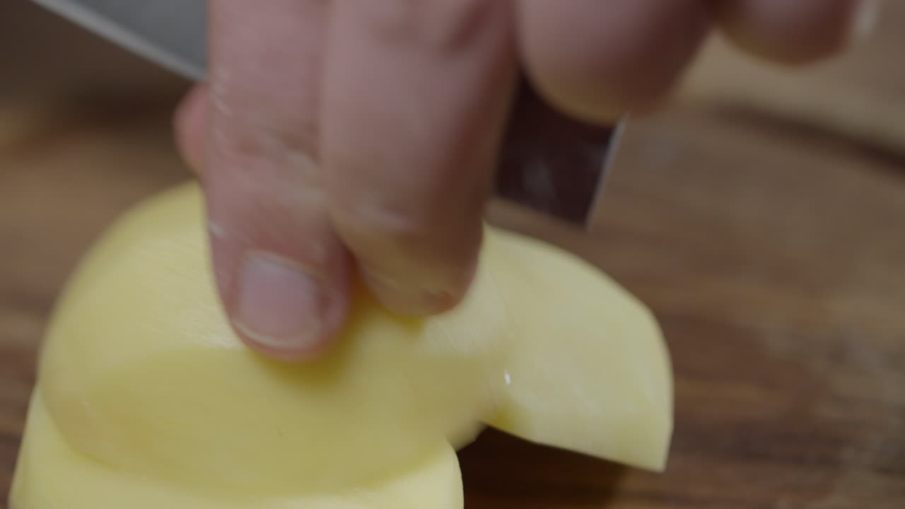 primer plano del chef cortando patatas crudas en rebanadas