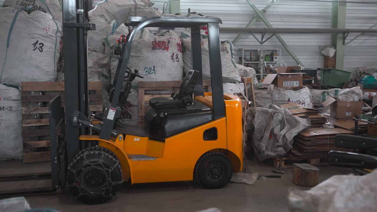 Yellow Forklift Parked Among Pallets And Debris, Idle Logistics Vehicle In Cluttered Recycling Warehouse, . Media