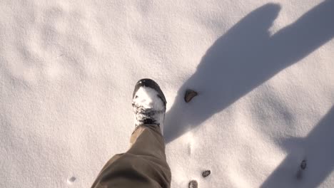 POV-shot-of-the-feet-of-a-hiker-walking-on-snow-in-a-mountain-of-Canada