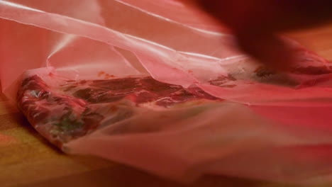 Close-up-of-wrapping-meat-in-parchment-paper-under-creepy-red-light