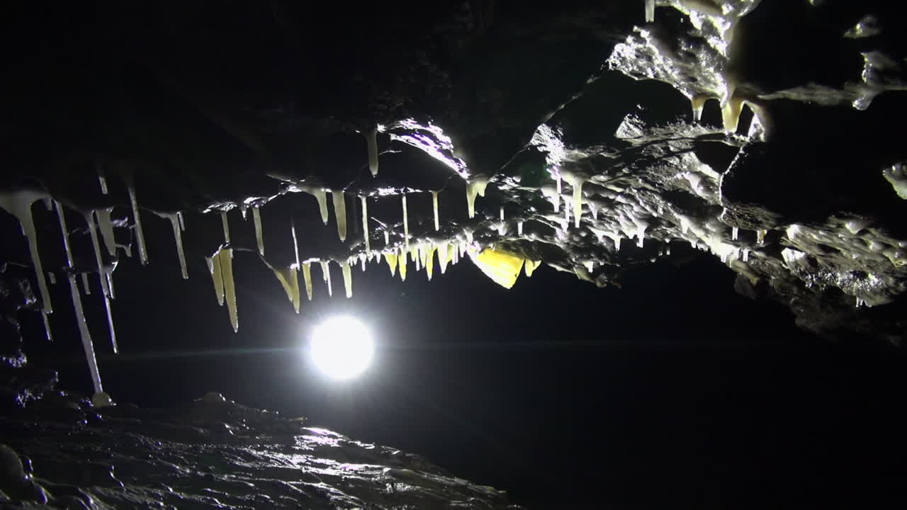 짙은 검은색 동굴 통로에 스펠레오템이 있는 백라이트 기울어진 천장