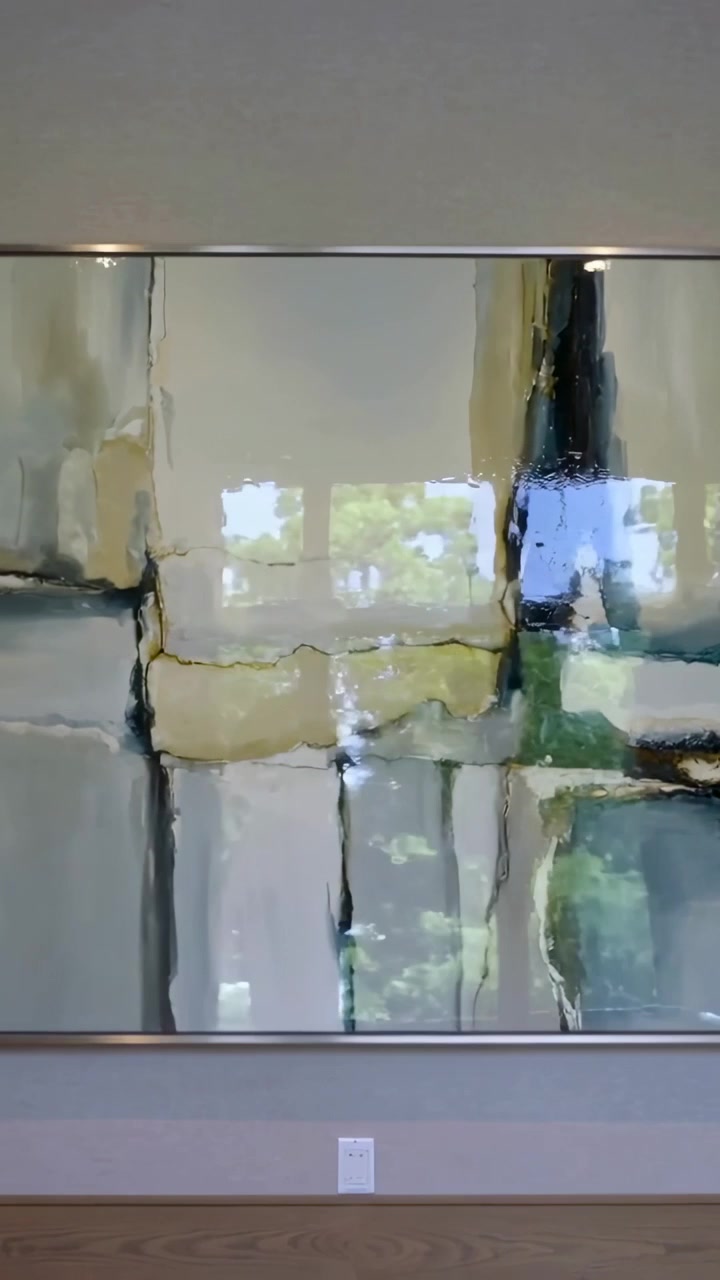 Vertical video: Panning camera right on lobby wall framed art showing window trees capturing shifts