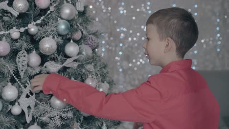 el niño mira y toca suavemente las bolas navideñas.