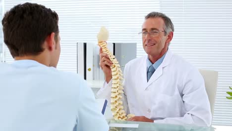 médico maduro hablando con su paciente sobre el modelo de columna vertebral