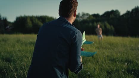 Man-playing-with-son-the-toy-airplane-at-meadow.