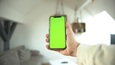 Un-Punto-De-Vista-De-Un-Hombre-Que-Sostiene-Un-Teléfono-Inteligente-Con-Pantalla-Verde-En-Posición-Vertical-En-Un-Fondo-Blanco-Aislado-Tocando-El-Teléfono