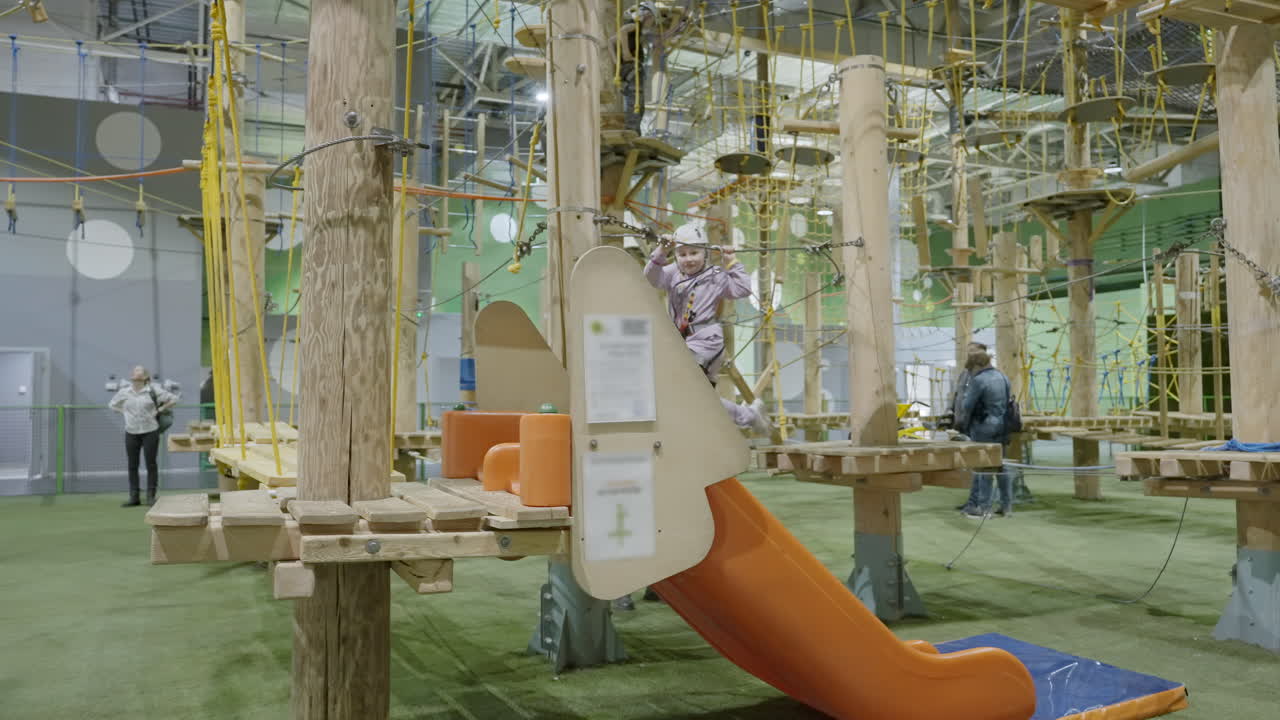 Child on an indoor ropes course at an adventure park