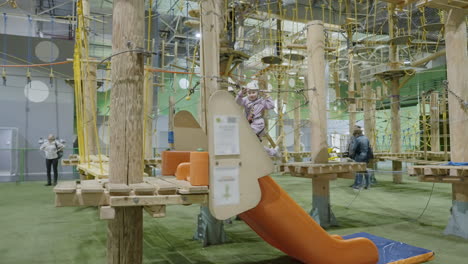 child on an indoor ropes course at an adventure park