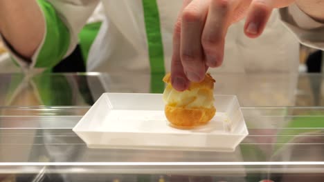 baker confectioner pipes fresh cream onto delicious delicatessen cake slide shot