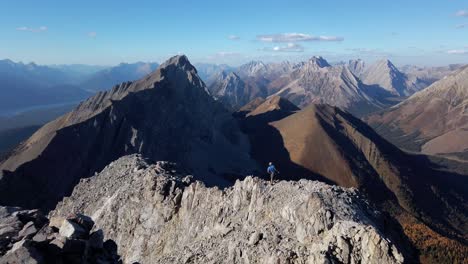 hiker on the edge cliff taking photos mountains kananaskis alberta british columbia border canada