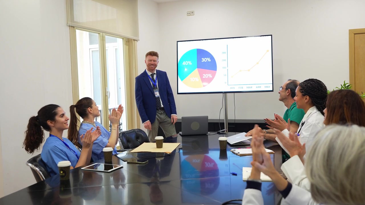 Medical Professionals Applaud Presenter During Business Meeting