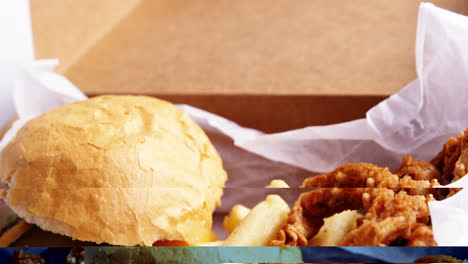 hamburger and french fries in a take away container on table