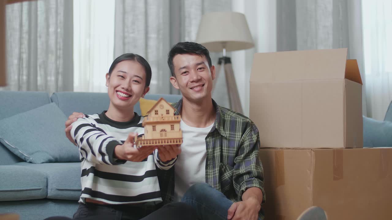 행복 한 부부 는 이사 하는 동안 모형 집 을 들고 있다