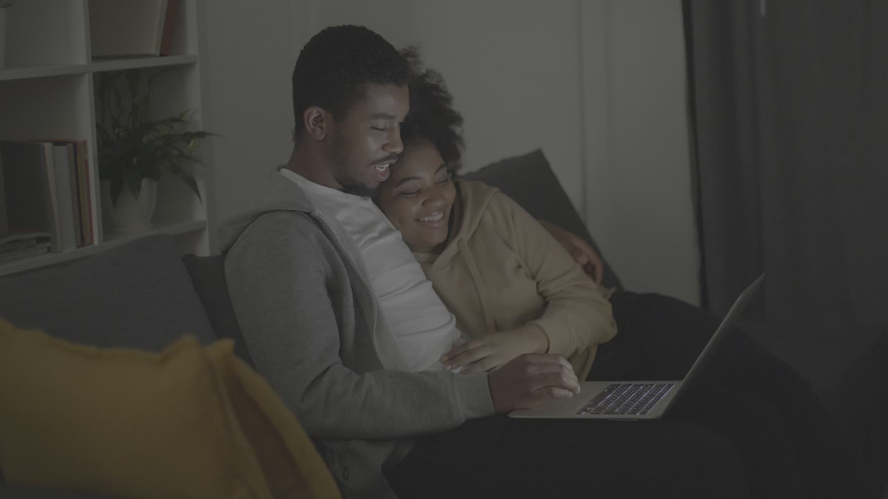 Young african american couple picking a programme or film to watch on the laptop