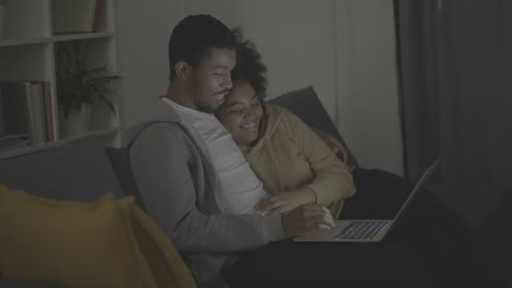 young african american couple picking a programme or film to watch on the laptop