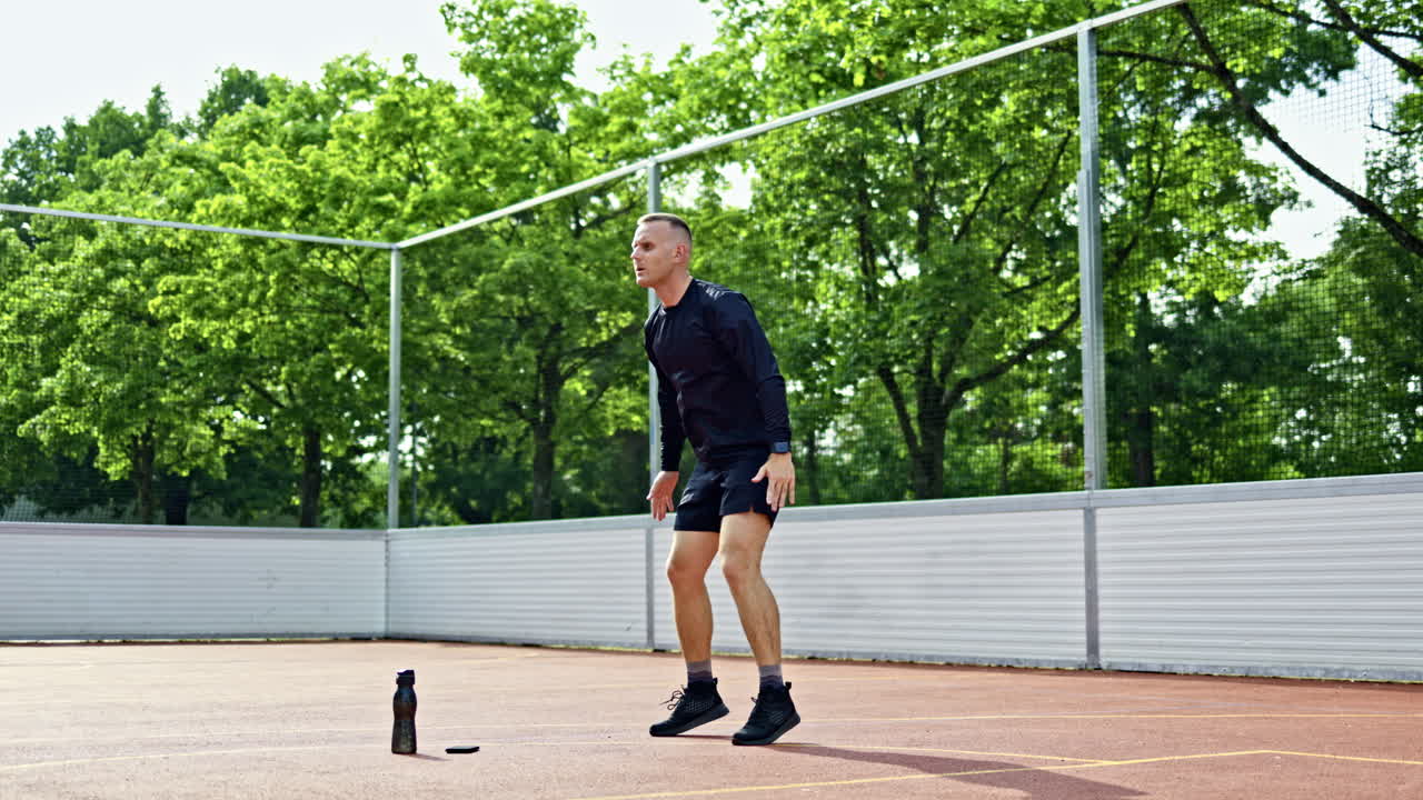 Pohledný muž v šortkách a tričku trénuje na sportovišti v parku. Muž trénuje venku. Sportovní životní styl.